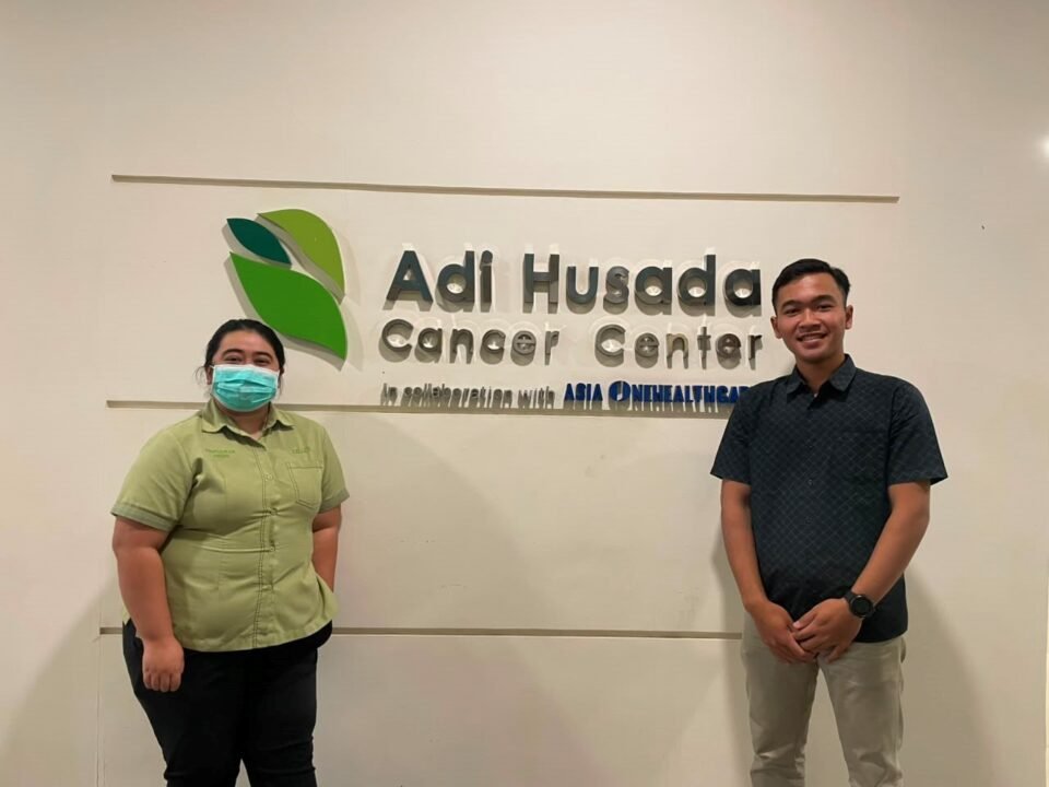 Dokumentasi Mahasiswa Bersama Pembimbing Lapangan di Depan Logo Adi Husada Cancer Center sebagai Lokasi Pelaksanaan Kegiatan Magang
