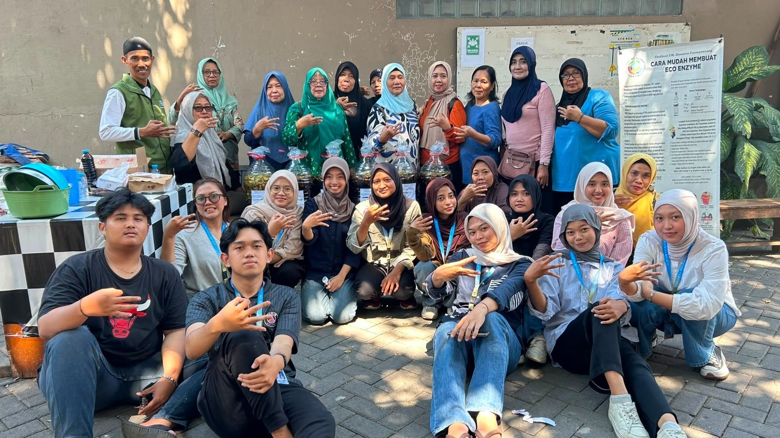 Mahasiswa KKN UPN Veteran Jawa Timur Kelompok 07 dan ibu-ibu PKK RW 03 Sawahan bersama botol eco-enzyme hasil kegiatan