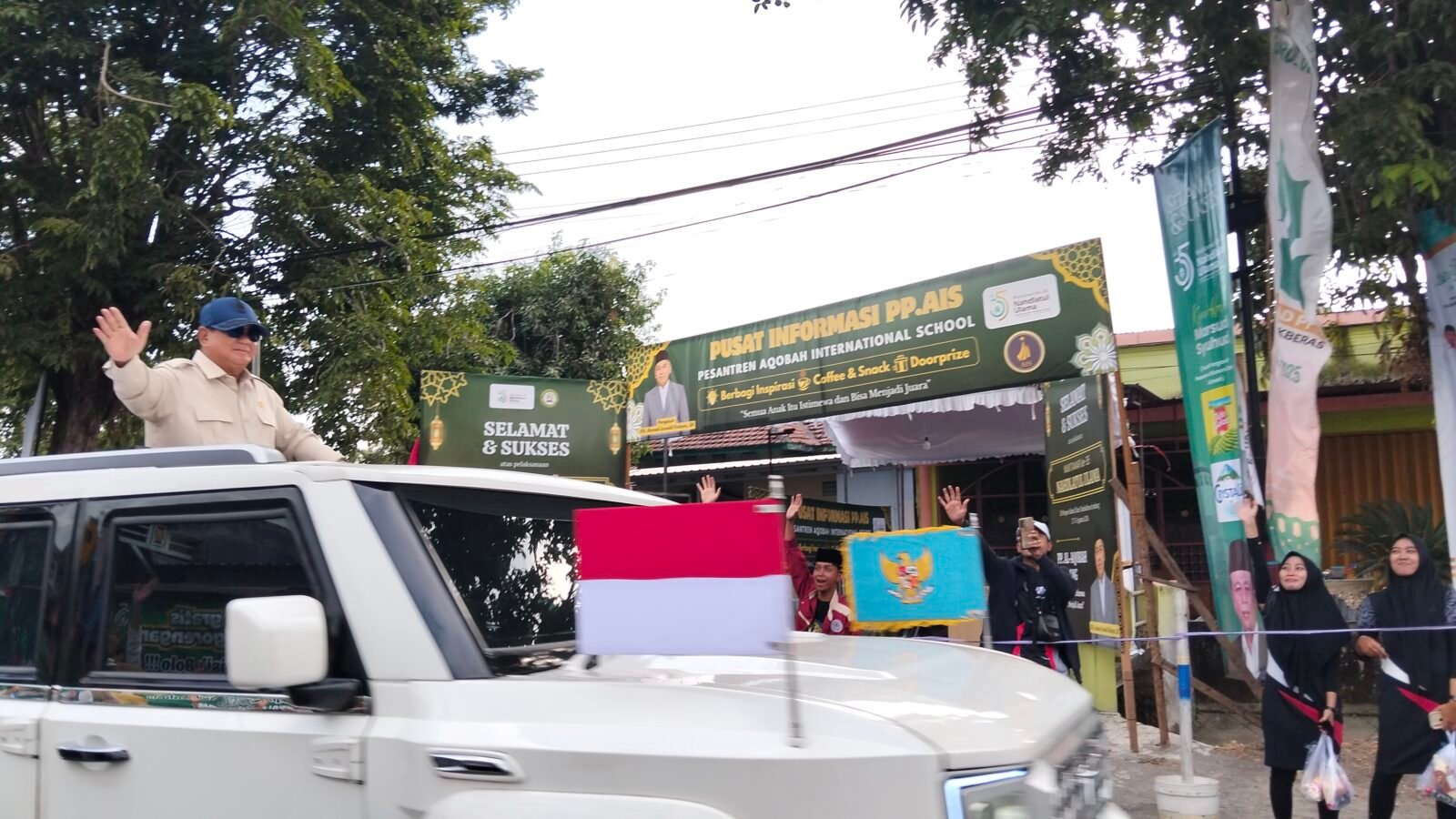 Presiden Prabowo menyapa warga dari kap mobil garuda