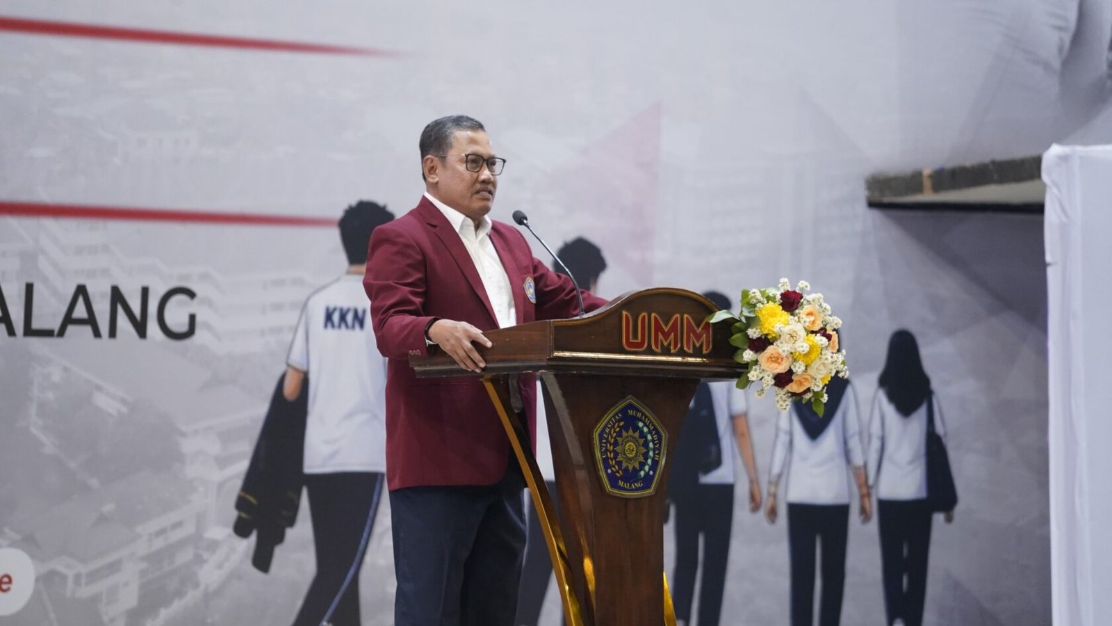 Pimpinan UMM tengah memberikan sambutan arahan di atas podium pada acara penutupan rangkaian KKN UMM 2026 yang berlangsung meriah di Hall Dome UMM