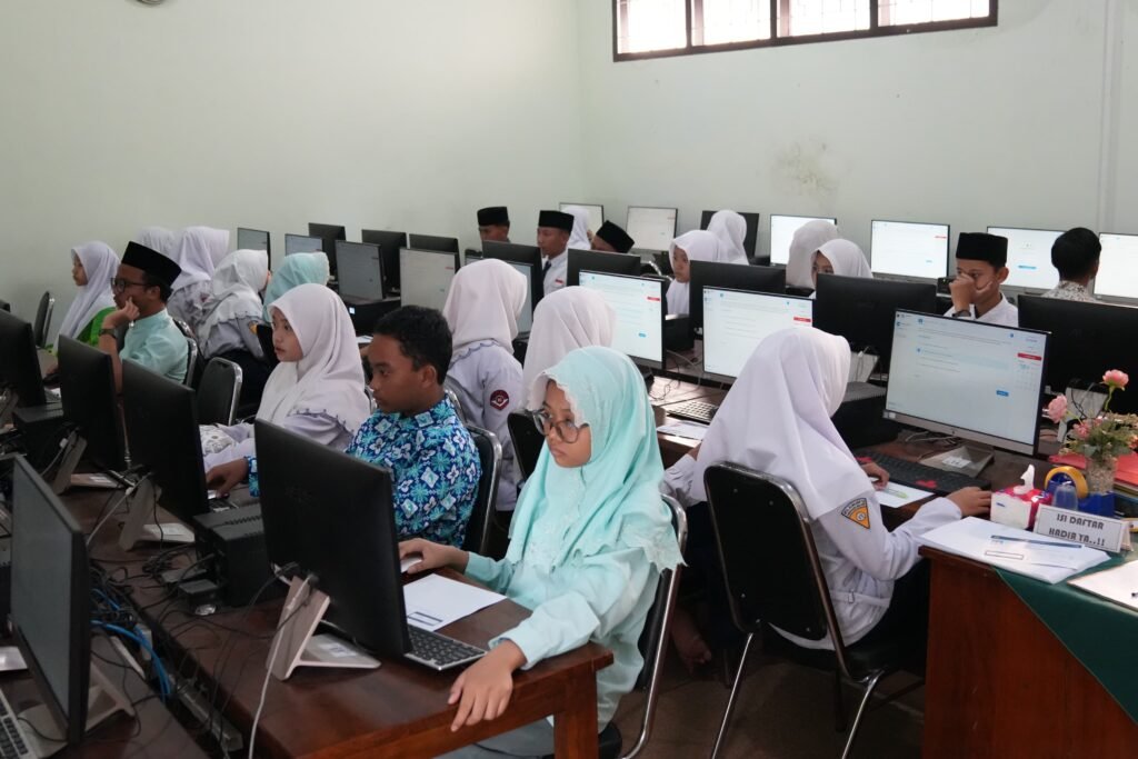 Suasana pelaksanaan Olimpiade Madrasah Indonesia (OMI) 2026 di titik lokasi MTs Almaarif 01 Singosari. Para peserta tampak fokus dan bersungguh-sungguh mengerjakan soal menggunakan sistem Computer Based Test (CBT).