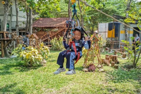 Salah seorang siswa RA Al Mustawa tampak ceria dan berani saat meluncur di wahana flying fox dengan pengamanan lengkap pada kegiatan outing class di Wisata Edukasi Mbedidhink Outbound, Graha BatuBeling, Bojonegoro.