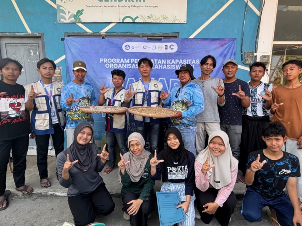 Tim PPK Ormawa BEM Unesa 2026 bersama para petambak, nelayan, dan pemuda Desa Labuhan berfoto bersama sambil memamerkan proses pengeringan ikan rucah dalam rangkaian program Bahari Adiguna, Sabtu (22/8/2026).