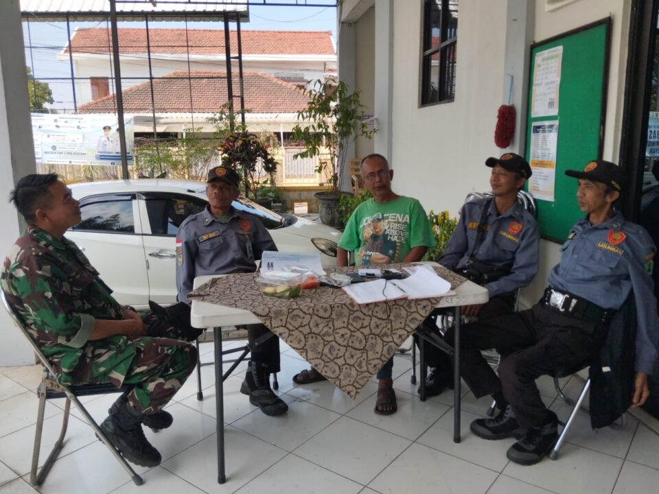 Babinsa Tulusrejo Koramil 0833-05/Lowokwaru, Serda Fajar (kiri), duduk santai sembari berdialog menyerap aspirasi dan berkoordinasi bersama anggota Linmas serta warga di Kelurahan Tulusrejo, Kota Malang, Minggu (20/9/2026).