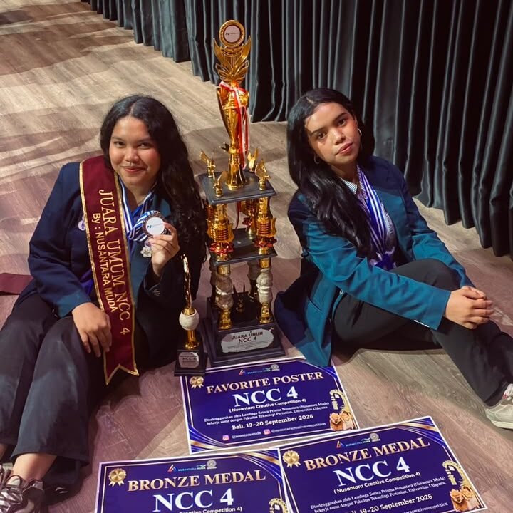 Dua mahasiswa delegasi FBiPK Universitas Brawijaya tersenyum bangga memamerkan piala Juara Umum, selempang kejuaraan, medali, serta sertifikat penghargaan Nusantara Creative Competition (NCC) 4 di Universitas Udayana, Bali.