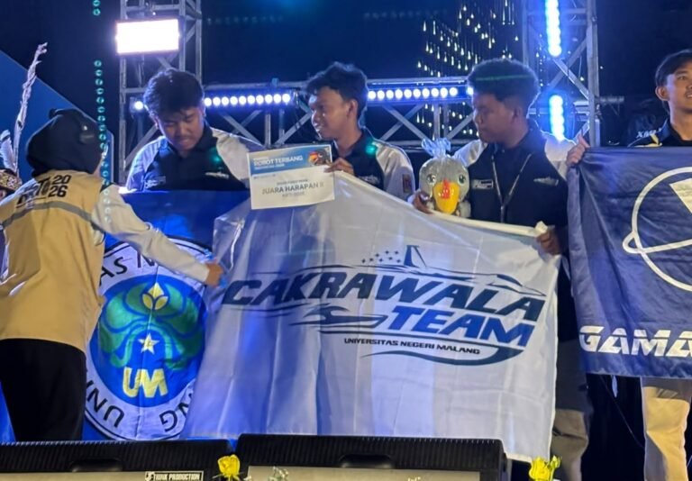 Delegasi Cakrawala Team 2 Universitas Negeri Malang membentangkan bendera kebanggaan usai berhasil meraih Juara Harapan II Divisi Fixed Wing pada ajang bergengsi Kontes Robot Terbang Indonesia (KRTI) 2026.