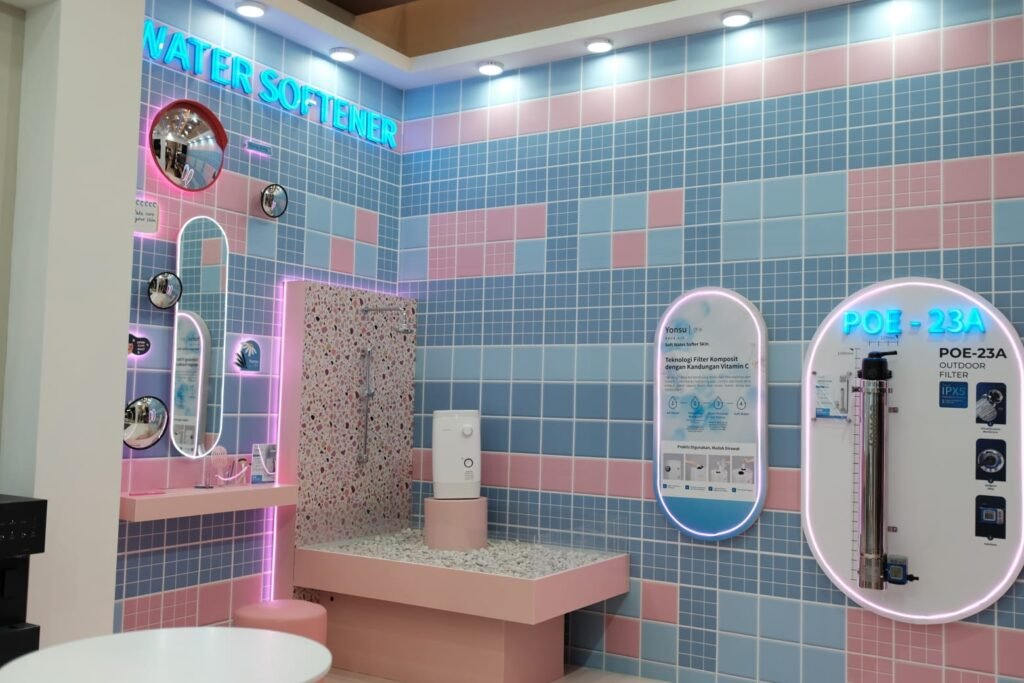 Tampilan stan Coway bernuansa pastel di ajang IndoBuildTech (IBT) Surabaya 2026 yang memamerkan produk terbaru water softener Yonsu serta sistem filter air luar ruangan POE-23A.