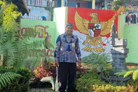 Risdiyan Tri Wahyudi di sudut Kampung Pancasila dengan latar mural Garuda Pancasila dan pelinggih, simbol kerukunan dan keberagaman warga