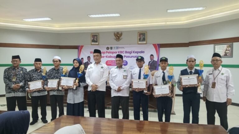 Para siswa berprestasi, termasuk peraih juara OMI 2026 dari MTsN 6 Pasuruan, berfoto bersama Plt. Kepala Kankemenag Pasuruan dan jajaran usai menerima piagam penghargaan serta piala.