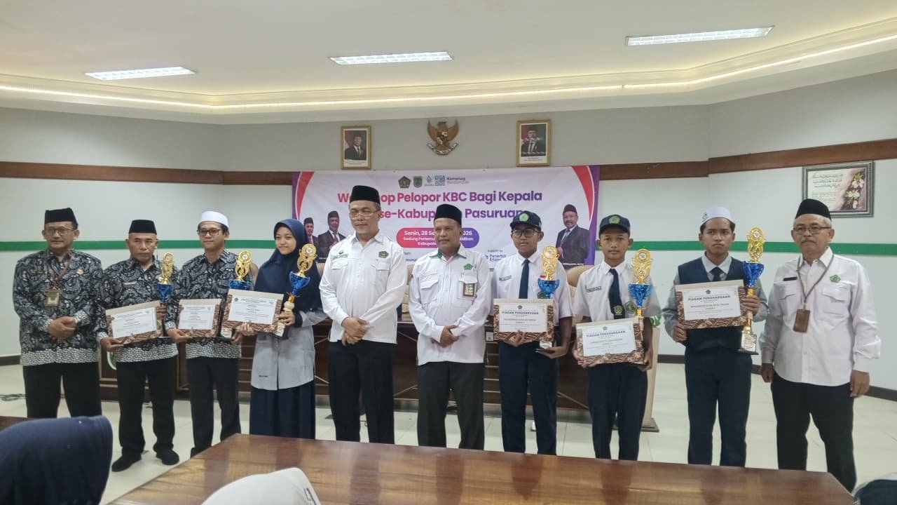Para siswa berprestasi, termasuk peraih juara OMI 2026 dari MTsN 6 Pasuruan, berfoto bersama Plt. Kepala Kankemenag Pasuruan dan jajaran usai menerima piagam penghargaan serta piala.