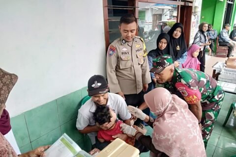 Babinsa Kotalama Koptu Eko bersama Bhabinkamtibmas mendampingi nakes saat memberikan suntikan imunisasi kepada balita dalam layanan Posyandu di Kotalama, Kedungkandang, Kota Malang, Jumat (18/09).