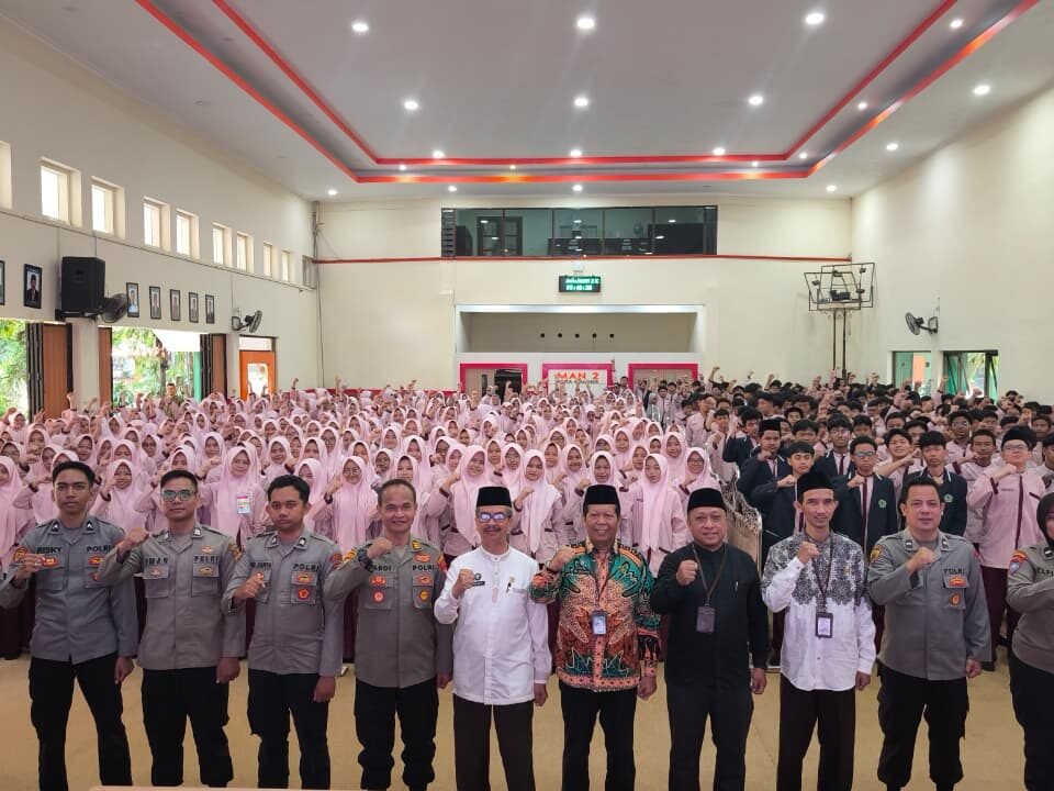 Jajaran personel Satbinmas Polresta Malang Kota bersama pejabat Kemenag dan pimpinan madrasah berfoto bersama ratusan siswa kelas X usai agenda Sosialisasi dan Simulasi Program Paham AI di Aula MAN 2 Kota Malang.