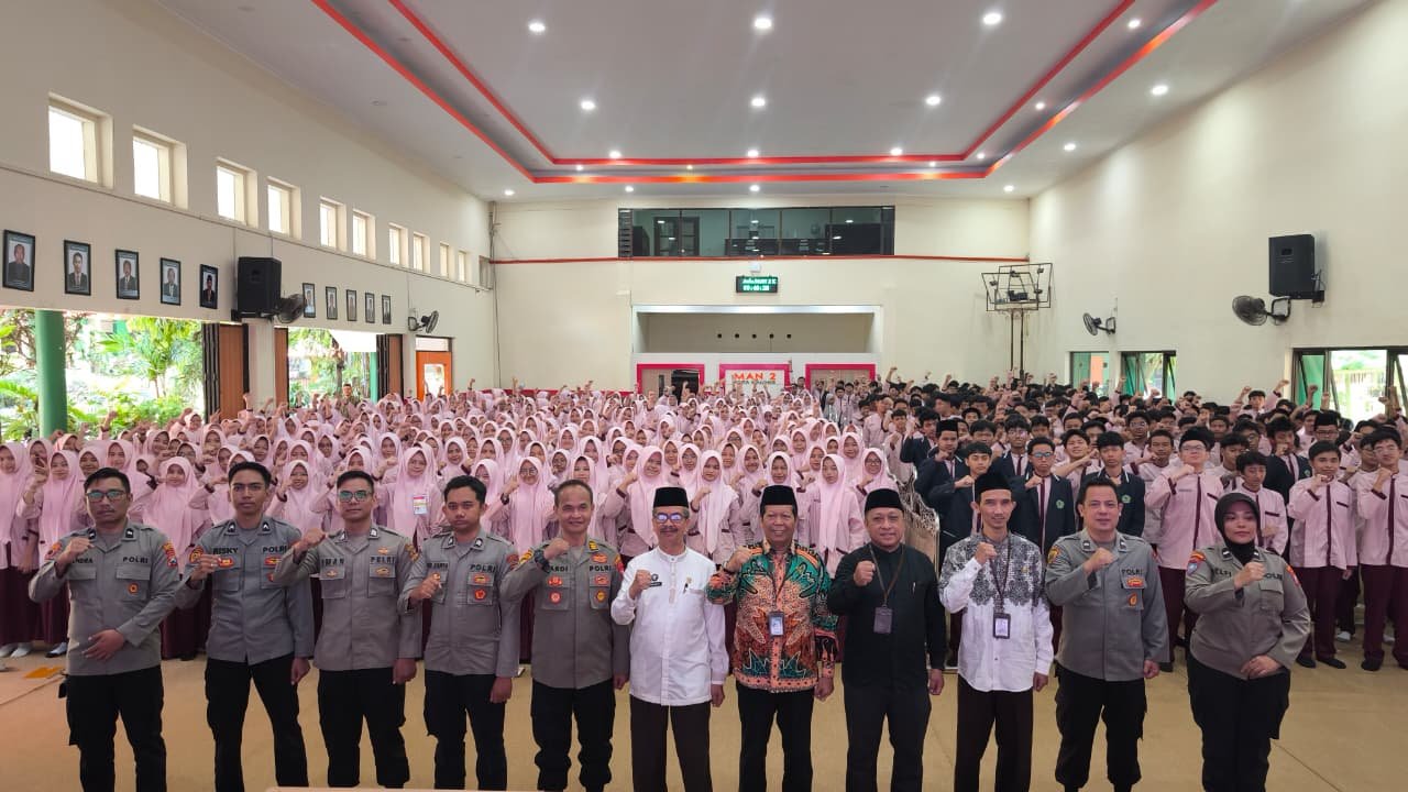 Jajaran personel Satbinmas Polresta Malang Kota bersama pejabat Kemenag dan pimpinan madrasah berfoto bersama ratusan siswa kelas X usai agenda Sosialisasi dan Simulasi Program Paham AI di Aula MAN 2 Kota Malang.