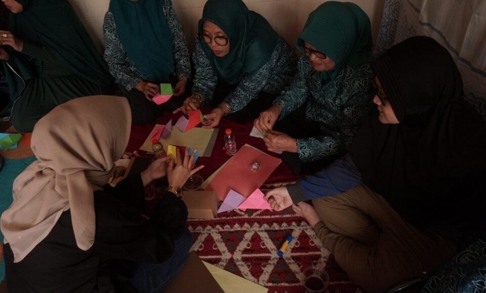 Suasana interaktif saat tim mahasiswa dan dosen Desain Interior UPN "Veteran" Jawa Timur memberikan pendampingan langsung kepada warga dalam menaklukkan kerumitan pola lipatan Origami Lamp.