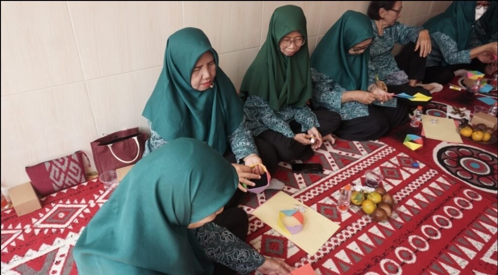 Keseriusan dan antusiasme ibu-ibu PKK RT 26 Desa Pabean, Sidoarjo, saat sibuk melipat dan merangkai kertas menjadi bentuk geometri tiga dimensi.