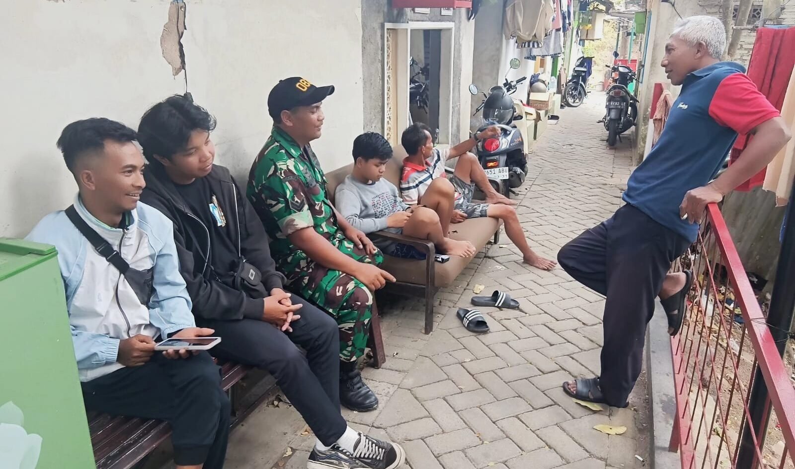 Babinsa Koramil 0833-01/Klojen, Sertu Gunawan, tampak membaur dan bercengkerama santai bersama warga di sebuah gang permukiman Kelurahan Klojen, Rabu (16/09/2026).
