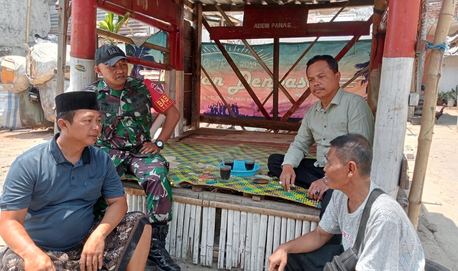 Babinsa Kotalama, Koptu Eko (berjaket loreng), tampak duduk bersama dan berbincang santai penuh kekeluargaan ditemani secangkir kopi bersama sejumlah warga di sebuah pos wilayah Kelurahan Kotalama, Kecamatan Kedungkandang, Kota Malang, Kamis (17/09/2026).