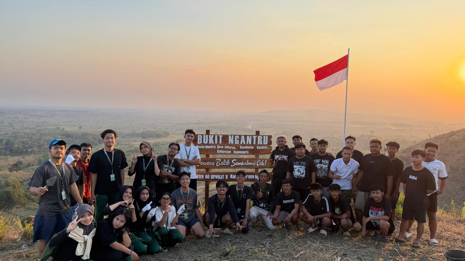 Mahasiswa KKN Kelompok 60 bersama anggota Karang Taruna Dusun Ngantru berfoto di depan plang penanda yang baru dipasang di puncak Bukit Ngantru, Desa Sekaran, Kecamatan Kasiman, Kabupaten Bojonegoro.