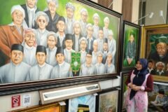 Anggota DPD RI asal Jawa Timur, Lia Istifhama, berpose di depan lukisan wajah-wajah para Muassis dan tokoh Nahdlatul Ulama setelah memenangkan lelang lukisan pada momen Muktamar ke-35 NU di Jombang.