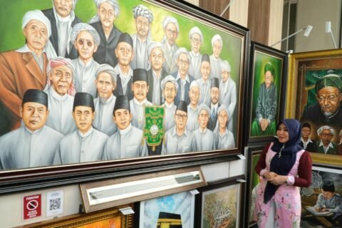 Anggota DPD RI asal Jawa Timur, Lia Istifhama, berpose di depan lukisan wajah-wajah para Muassis dan tokoh Nahdlatul Ulama setelah memenangkan lelang lukisan pada momen Muktamar ke-35 NU di Jombang.
