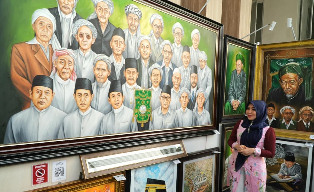 Anggota DPD RI asal Jawa Timur, Lia Istifhama, berpose di depan lukisan wajah-wajah para Muassis dan tokoh Nahdlatul Ulama setelah memenangkan lelang lukisan pada momen Muktamar ke-35 NU di Jombang.