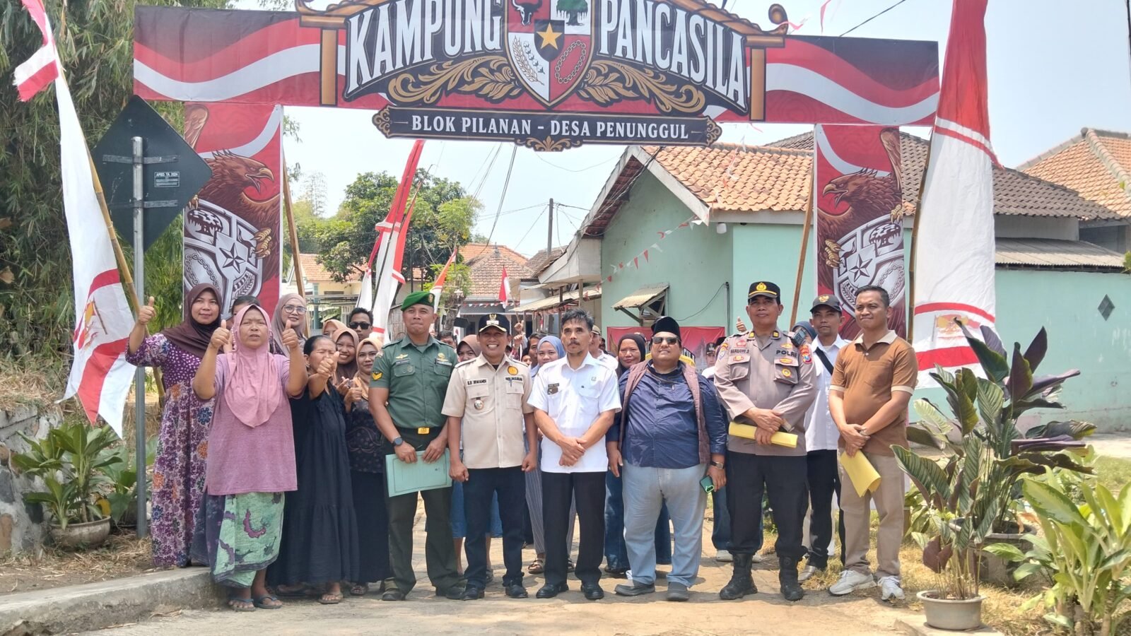 Potret antusiasme dan kebersamaan warga bersama elemen pemerintah desa, TNI, serta Polri di bawah gapura Blok Pilanan saat menyambut tim penilai Lomba Kampung Pancasila di Desa Penunggul.