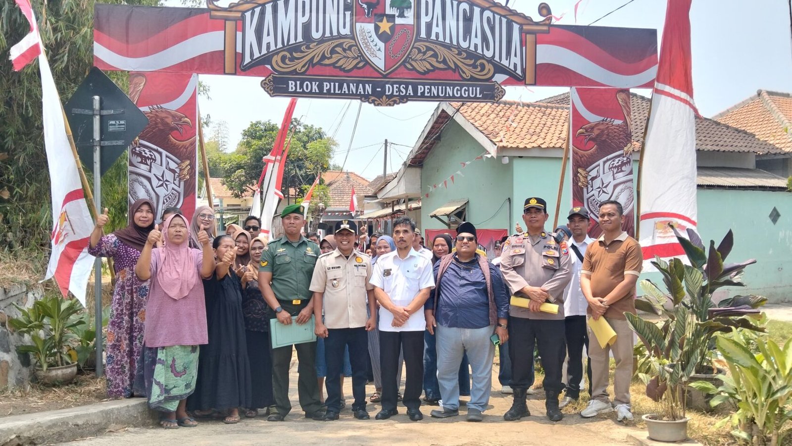 Potret antusiasme dan kebersamaan warga bersama elemen pemerintah desa, TNI, serta Polri di bawah gapura Blok Pilanan saat menyambut tim penilai Lomba Kampung Pancasila di Desa Penunggul.