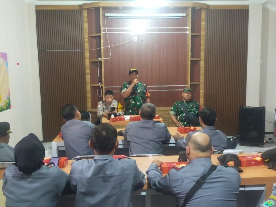Babinsa Kelurahan Klojen Sertu Gunawan berdiri memberikan arahan dan pembekalan tugas ketertiban wilayah kepada anggota Satlinmas di aula pertemuan, Klojen, Kota Malang.