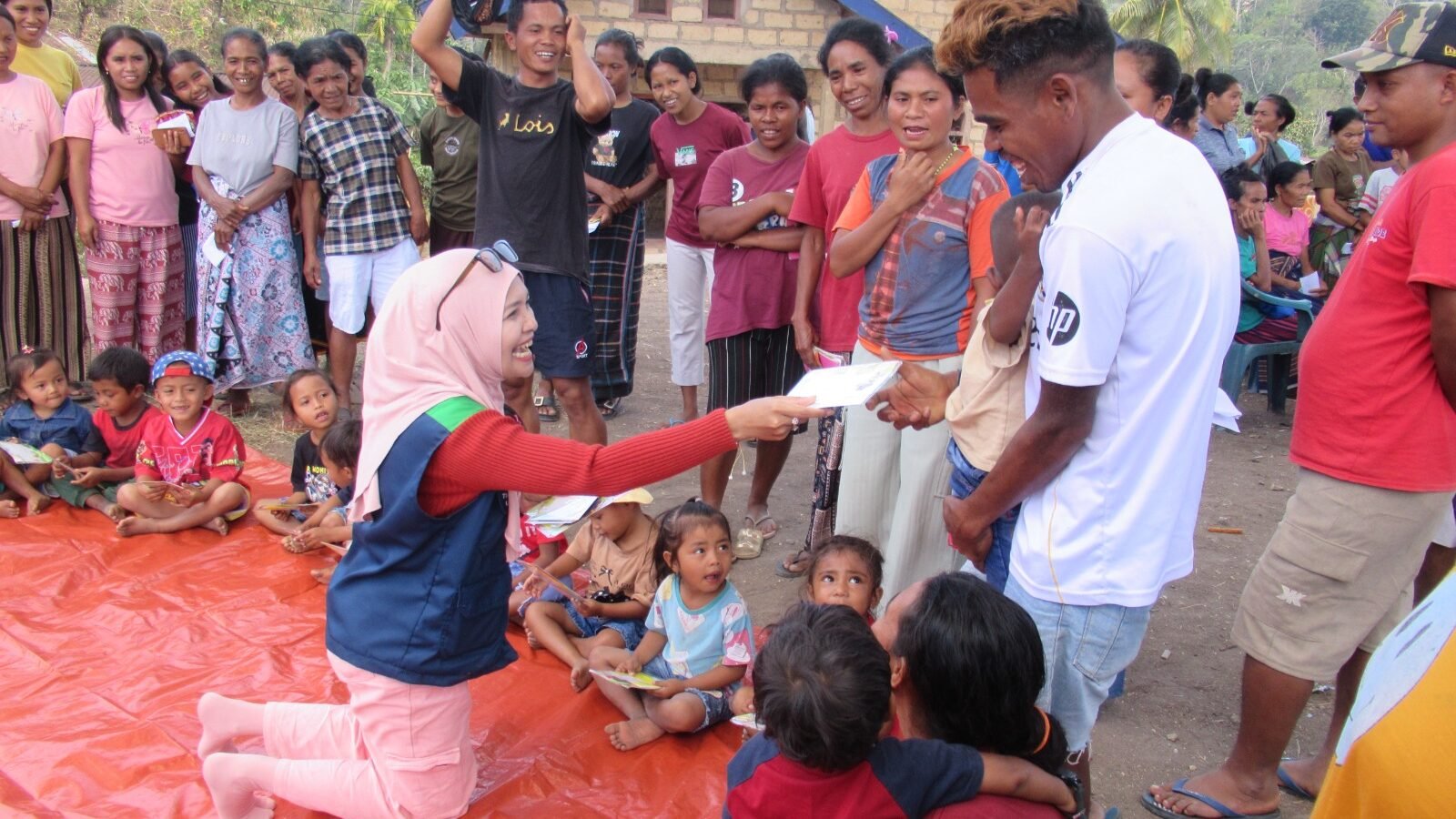 Seorang anggota Tim Relawan Bencana Universitas Negeri Malang (UM) tampak berinteraksi hangat sembari membagikan kertas lipat kepada anak-anak dan warga terdampak gempa dalam sesi Play Therapy di Desa Watunggong, Manggarai Timur.