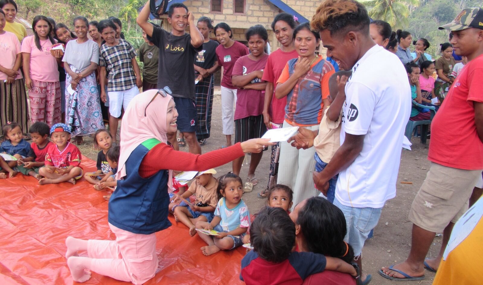 Seorang anggota Tim Relawan Bencana Universitas Negeri Malang (UM) tampak berinteraksi hangat sembari membagikan kertas lipat kepada anak-anak dan warga terdampak gempa dalam sesi Play Therapy di Desa Watunggong, Manggarai Timur.