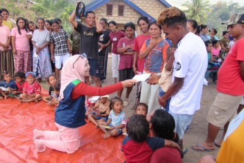 Seorang anggota Tim Relawan Bencana Universitas Negeri Malang (UM) tampak berinteraksi hangat sembari membagikan kertas lipat kepada anak-anak dan warga terdampak gempa dalam sesi Play Therapy di Desa Watunggong, Manggarai Timur.