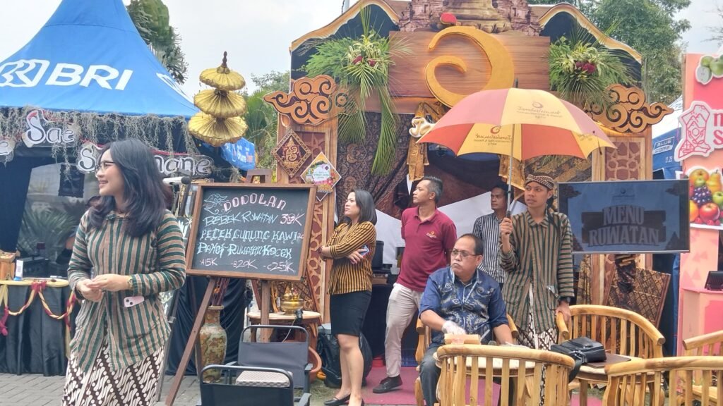 Petugas stan berpakaian adat lurik tradisional melayani pengunjung yang menikmati sajian kuliner khas lokal dalam rangkaian Festival Pangan dan KTNA Agro Expo 2026 di Kota Batu.