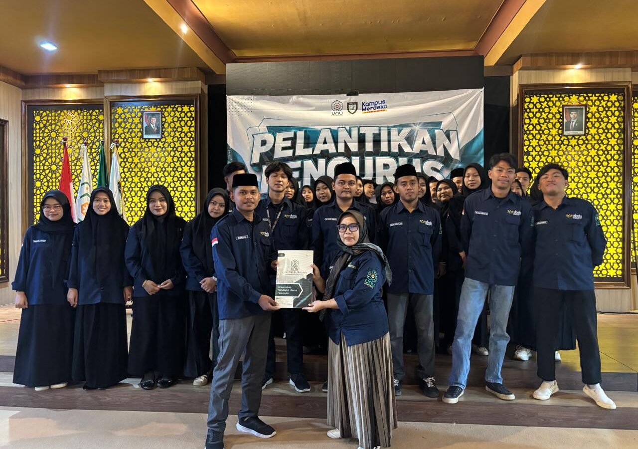 Ketua Program Studi PAI UNU Pasuruan, Ning Mukaromah, menyerahkan dokumen secara simbolis kepada Ketua HMPS PAI terpilih, Burham, didampingi jajaran pengurus baru usai prosesi pelantikan periode 2026/2027 di Gedung ITC.