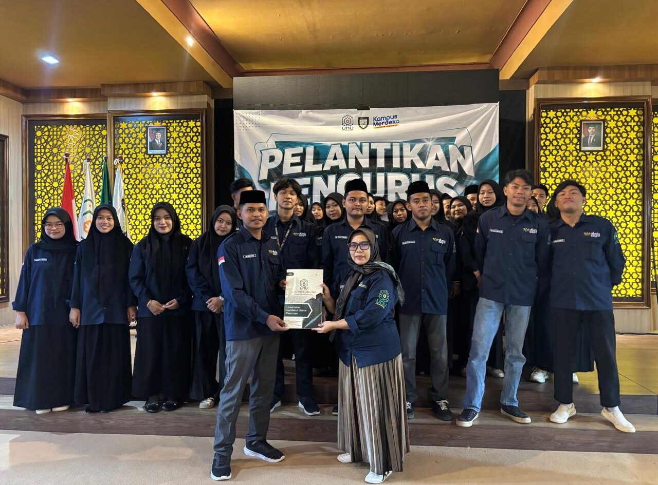 Ketua Program Studi PAI UNU Pasuruan, Ning Mukaromah, menyerahkan dokumen secara simbolis kepada Ketua HMPS PAI terpilih, Burham, didampingi jajaran pengurus baru usai prosesi pelantikan periode 2026/2027 di Gedung ITC.