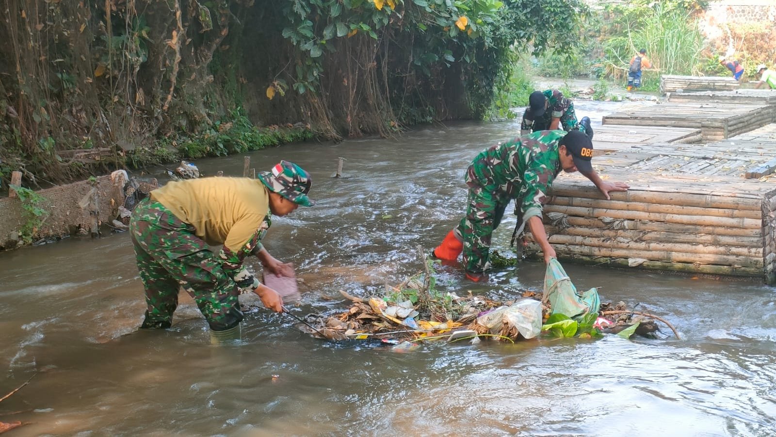 Anggota Koramil 0833-01/Klojen terjun langsung ke aliran sungai untuk membersihkan sampah yang menumpuk bersama warga di kawasan Kelurahan Kauman, Kecamatan Klojen, Kota Malang, Sabtu (19/9/2026).