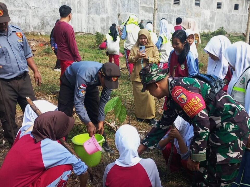 Momen kebersamaan personel Koramil 0833-03/Blimbing bersama petugas Linmas dan siswa-siswi SMPN 24 Malang saat bergotong royong menanam bibit pohon di Kelurahan Polowijen sebagai wujud aksi Karya Bakti memperingati HUT ke-81 TNI.