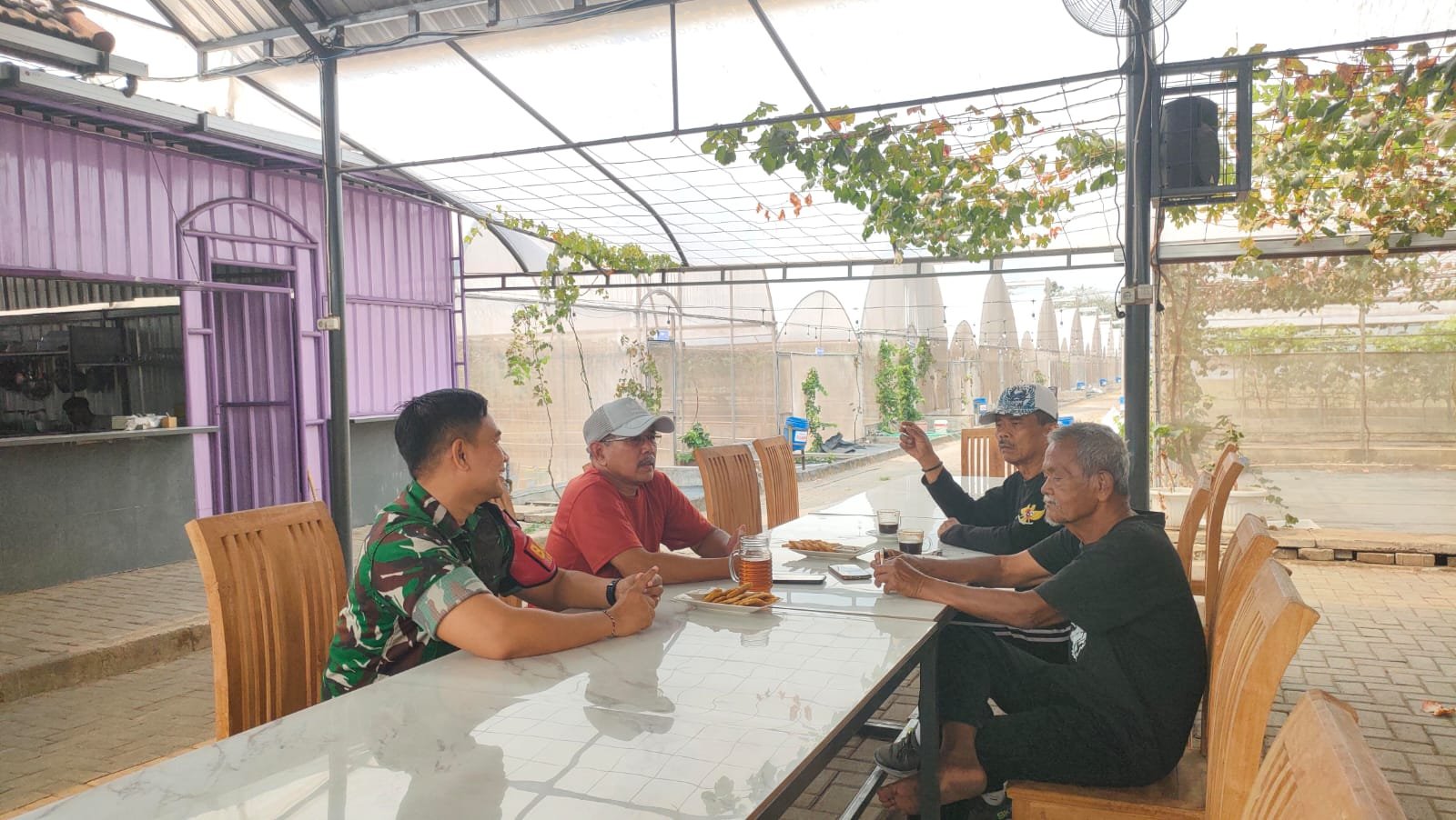 Babinsa Kelurahan Bareng, Serda Putu (kiri), tampak berbincang santai dan penuh keakraban bersama sejumlah tokoh masyarakat dalam kegiatan Komsos guna membahas keamanan dan ketertiban lingkungan, Kamis (10/09).