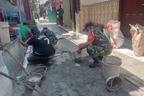 Babinsa Kotalama, Koptu Eko, bersama warga setempat, bahu-membahu memperbaiki jalan kampung yang rusak dengan adukan semen di wilayah Kedungkandang, Malang.**