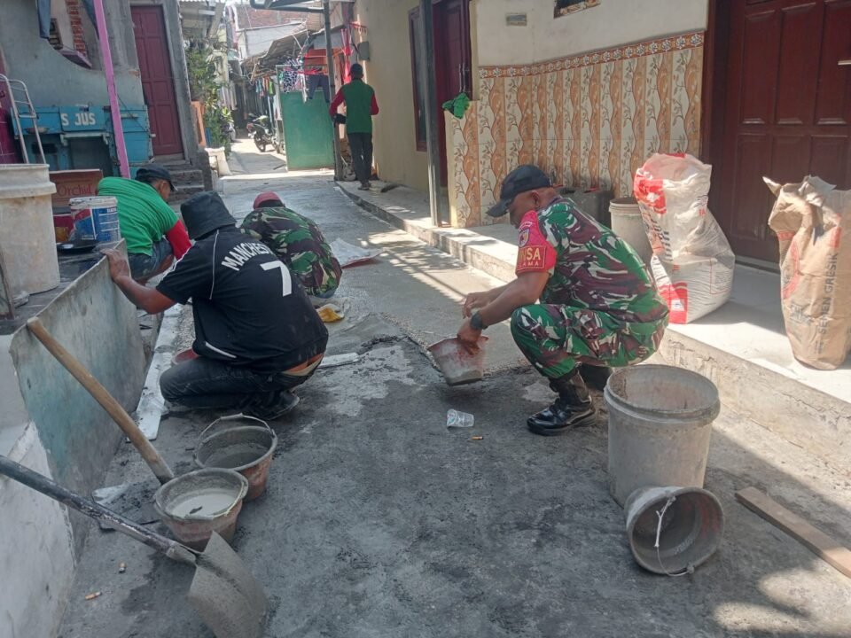 Babinsa Kotalama, Koptu Eko, bersama warga setempat, bahu-membahu memperbaiki jalan kampung yang rusak dengan adukan semen di wilayah Kedungkandang, Malang.**