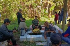 Babinsa Blimbing, Sertu Gede (tengah, seragam loreng), tampak tertawa lepas dan berbincang hangat bersama warga sambil menikmati suguhan sederhana usai kerja bakti membersihkan TPU Kelurahan Blimbing, Kota Malang, Kamis (17/09/2026).