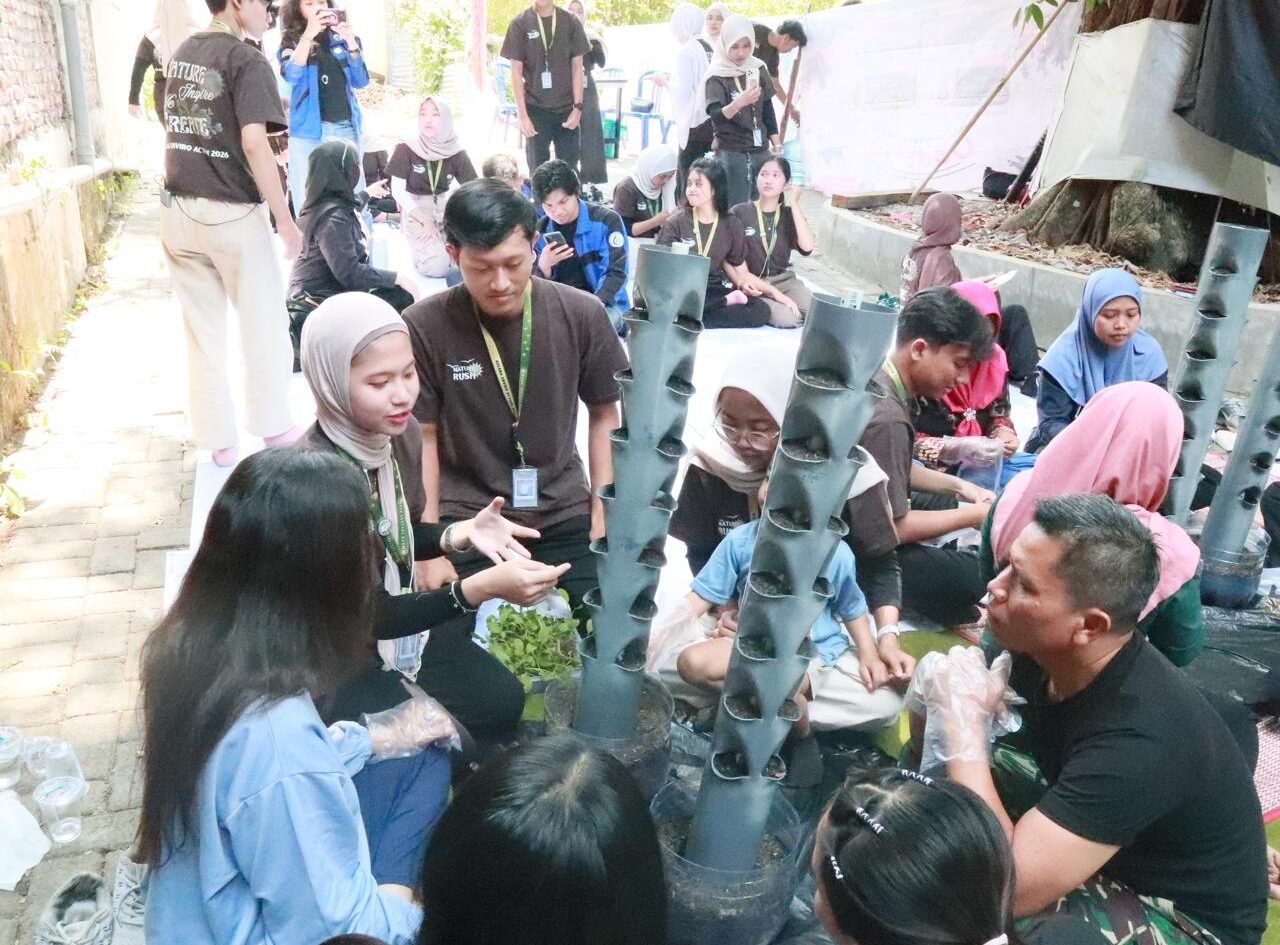 Kolaborasi antargenerasi dalam program MEA 2026: Mahasiswa KMTL FTAB UB dan warga RW 06 Tunjungsekar antusias mempelajari praktik penanaman pada model vertical garden berbahan pipa PVC, sebagai solusi penghijauan produktif di lahan sempit perkotaan.