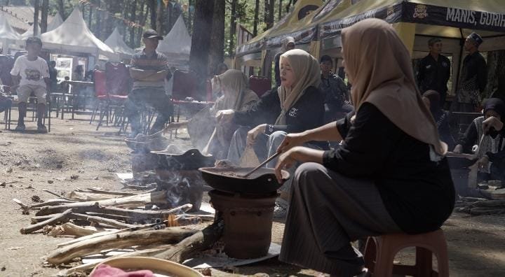 Peserta wanita antusias mengikuti Kreweng Competition dengan mengolah biji kopi secara tradisional menggunakan tungku tanah liat dan kayu bakar.