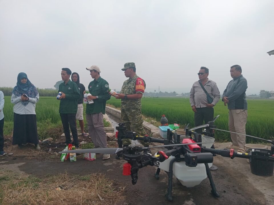 Babinsa Arjowinangun bersama tim PPL dan kelompok tani saat bersiap melakukan penyemprotan padi menggunakan drone.