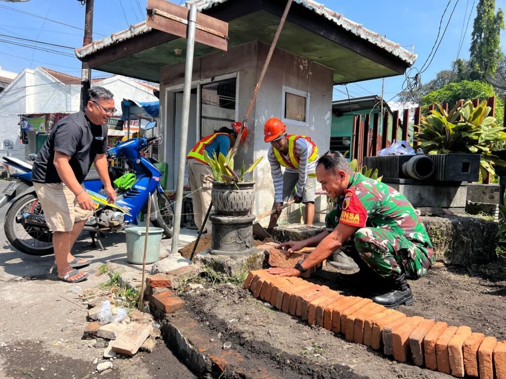 Babinsa Ketawanggede Koramil 0833-05/Lowokwaru, Sertu Santoso, turut turun langsung membantu warga membangun taman fasilitas umum