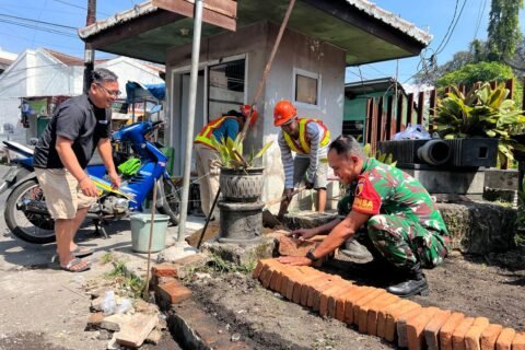 Babinsa Ketawanggede Koramil 0833-05/Lowokwaru, Sertu Santoso, turut turun langsung membantu warga membangun taman fasilitas umum