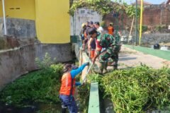 Babinsa Tulusrejo Serda Fajar bersama warga gotong royong membersihkan sampah dan lumpur di saluran air untuk cegah banjir.