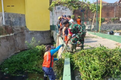Babinsa Tulusrejo Serda Fajar bersama warga gotong royong membersihkan sampah dan lumpur di saluran air untuk cegah banjir.