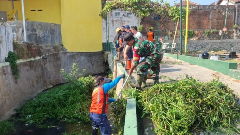 Babinsa Tulusrejo Serda Fajar bersama warga gotong royong membersihkan sampah dan lumpur di saluran air untuk cegah banjir.