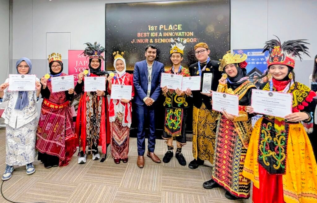 Group 5 delegasi MAN 2 Kota Malang dengan balutan busana adat Nusantara berpose bangga bersama sertifikat dan trofi 1st Place Best Idea Innovation.