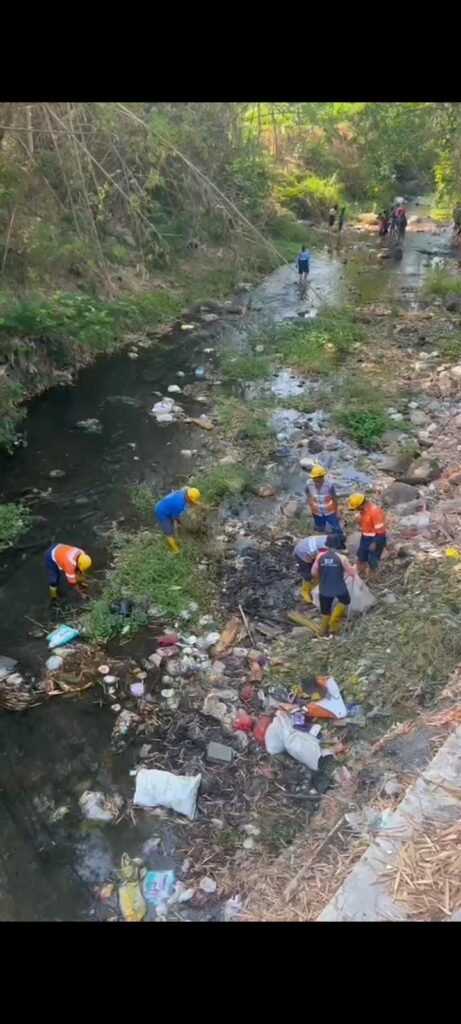 Personel DLH terjun langsung ke aliran sungai untuk mengangkat tumpukan sampah plastik dan limbah guna menjaga kebersihan sumber air di kawasan Sumber Merjosari.